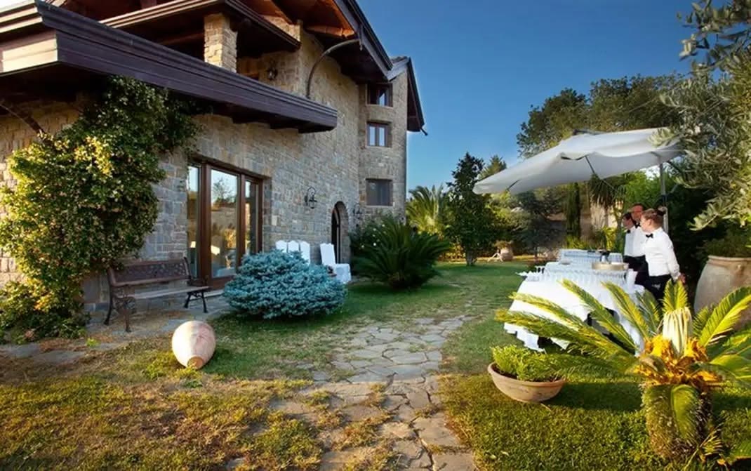 Il casale in pietra della tenuta visto dal giardino, con il buffet allestito all'aperto