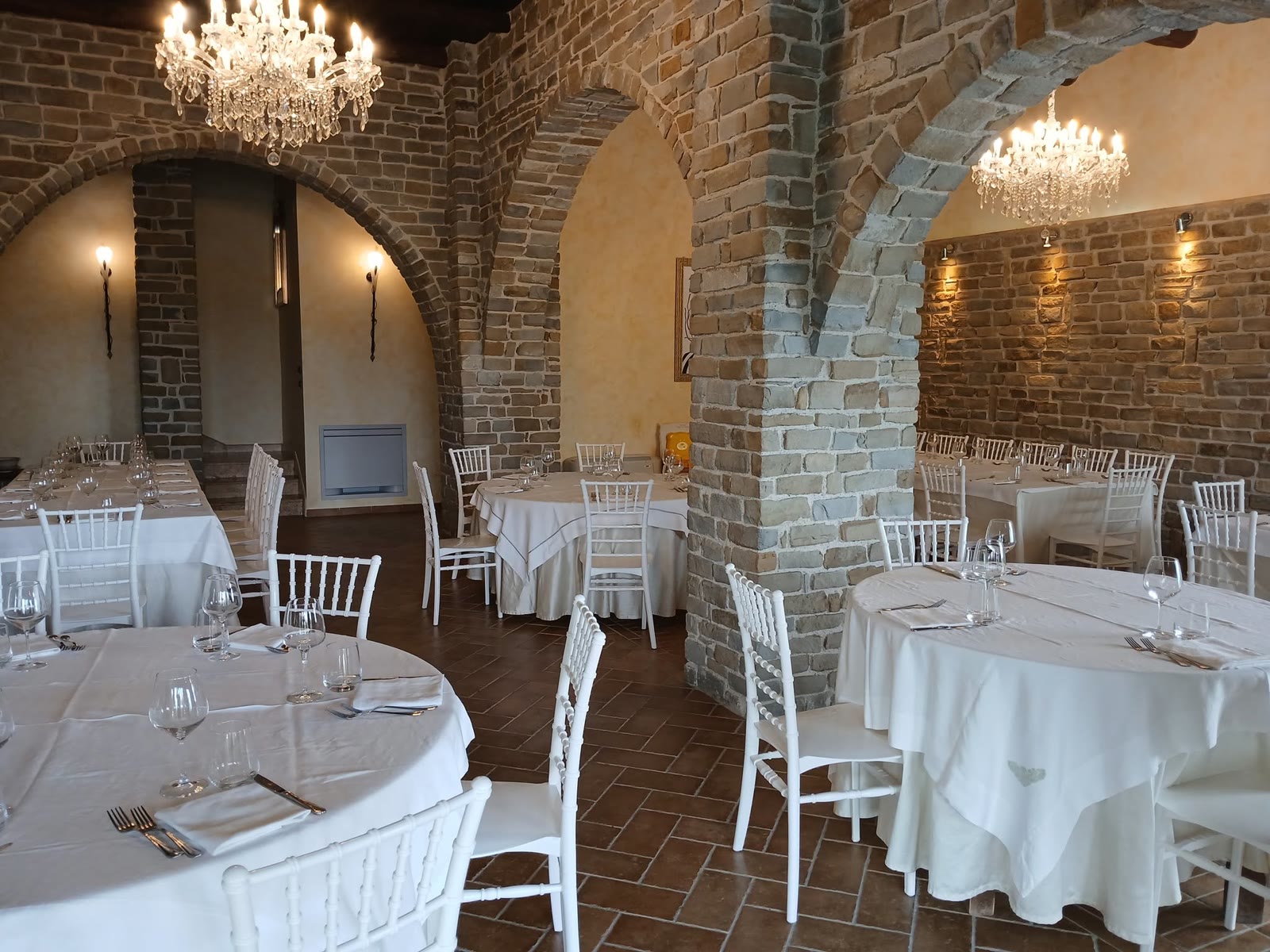 Il salone interno con gli archi in pietra, i lampadari di cristallo e i tavoli rotondi apparecchiati